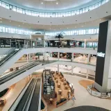 Interior de un moderno centro comercial en Valencia, con escaleras mecánicas, palmeras y tiendas. Un lugar ideal para ir de compras.