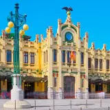 Estació del Nord Valencia, edificio modernista amarillo con detalles verdes y rojos, reloj y águila en la fachada.
