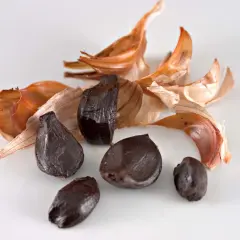 Dientes de ajo negro, con cáscaras secas de color naranja y blanco, evocan el sabor único del ajo negro alicante.
