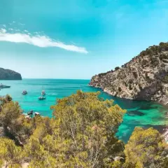 Unas calas de ensueño en la Costa Blanca, con aguas turquesas, vegetación exuberante y barcos navegando.