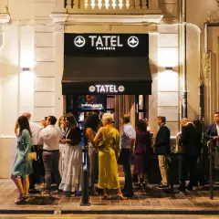 Gente elegante espera en la entrada de Tatel Valencia, un local nocturno iluminado.