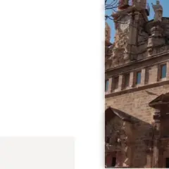 Edificio histórico en Alicante, parte de la ruta de la seda. Fachada de piedra con reloj y detalles ornamentales.