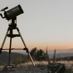 Telescopi preparat per a un sopar amb estrelles. El cel s'enfosqueix sobre les muntanyes, prometent una nit d'observació celestial.
