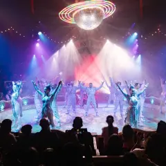 Artistas del circo Raluy en Alicante, bajo una bola de discoteca, con confeti cayendo y público aplaudiendo.