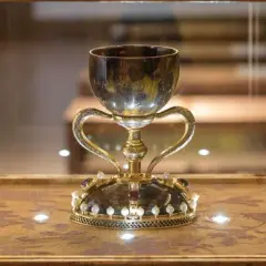 Cáliz dorado con asas, adornado con perlas y gemas, exhibido en vitrina. ¿Será este donde está el santo grial?