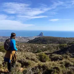 Senderista contempla el Peñón de Ifach y la costa desde una de las rutas de Calpe.
