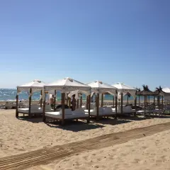 Días soleados en la playa Carabassi, con toldos blancos y camas de día listas para el relax junto al mar azul.