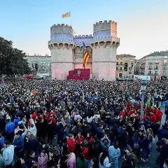 Multitudinaria **la crida valencia** ante las Torres de Serranos, con banderas valencianas ondeando y un escenario preparado.