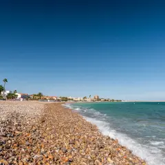 La playa Gurugú de Benicarló, con su guijarro y palmeras, invita a un día soleado junto al mar Mediterráneo.