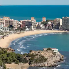 Vista panorámica de la **playa de la Concha Oropesa**, con edificios residenciales, el mar azul y una costa rocosa.