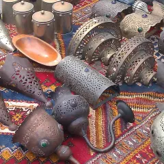 Lámparas y recipientes metálicos decorados, con un cuenco de madera, expuestos en un mercadillo de Polop.