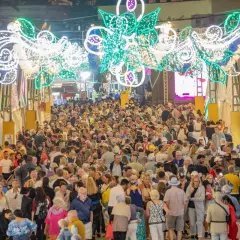 Multitudinaria feria nocturna con arcos de luces y puestos.
