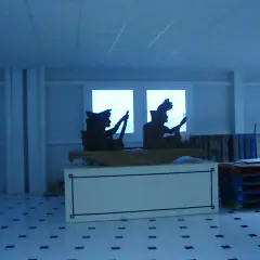 Siluetas de figuras en un interior, quizás una fábrica valor Alicante, con palets y un extintor.