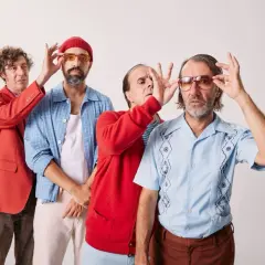Cuarteto de Nos en Valencia, con gafas de sol y atuendos coloridos, listos para un concierto.