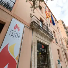 Fachada del Museu Faller de València con un cartel anunciador y banderas ondeando.