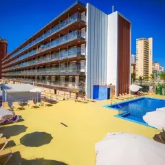 Terraza soleada con piscina y tumbonas en el hotel Diplomatic Benidorm. Edificio moderno con balcones y palmeras.