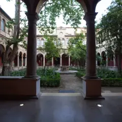 Patio interior con arcos y columnas en el barrio del Carmen, Valencia. Jardín frondoso con fuente central y árboles.