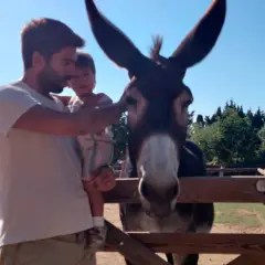 Un padre y su hijo visitan un burro en la granja escola corral de neri.
