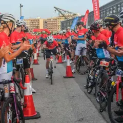 Ciclistas compiten en un gran fondo en Valencia. El público anima a los participantes mientras uno cruza la meta.
