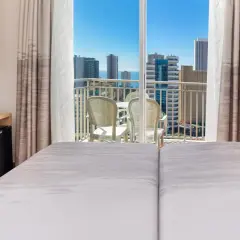 Habitación de hotel pueblo Benidorm con vistas al mar y rascacielos. Balcón con mesa y sillas. Escritorio con silla roja y minibar.