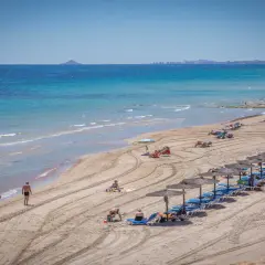 Una hermosa playa de mil palmeras con gente disfrutando del sol y el mar turquesa.