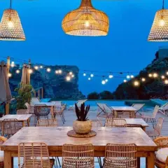 Un rincón de ensueño en el **dreamsea mediterranean camp**. Mesas de madera, sillas de ratán y luces cálidas bajo un cielo estrellado.