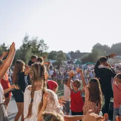 Niños y adultos con las manos en alto, disfrutando de las fiestas Valencia al aire libre.