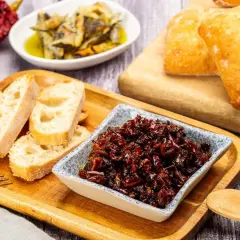 Pericana receta: pan rústico, pimientos secos y un cuenco con la deliciosa pericana, lista para untar.