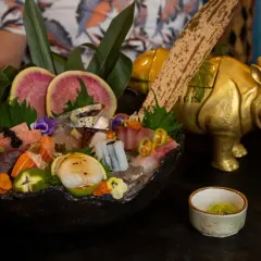 Un festín de sashimi en uno de los restaurantes temáticos de Valencia, con un rinoceronte dorado de decoración.
