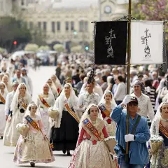 Procesión de mujeres con trajes tradicionales valencianos, celebrando cuando es San Vicente en Valencia.