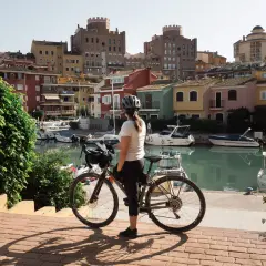 Ciclista en Valencia, disfrutando de las rutas ciclistas junto a un canal con casas coloridas y barcos.