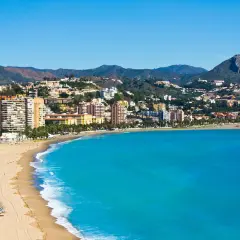 Vista panorámica de zonas de Alicante con playa, edificios altos y montañas al fondo.