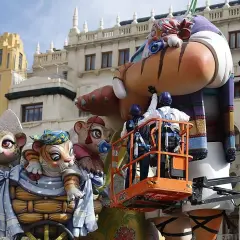 Dos operarios en una grúa trabajan en una falla gigante con figuras de animales. Se acerca el momento cuando es la planta.