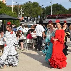 Mujeres con trajes de flamenca en la feria de abril de Valencia. Ambiente festivo con gente disfrutando.