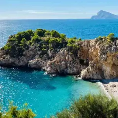 Una cala escondida con aguas turquesas y rocas escarpadas, un rincón idílico entre las mejores calas de Altea.