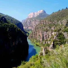 Impresionante desfiladero de Mont-rebei, con un río de aguas turquesas serpenteando entre imponentes paredes rocosas cubiertas de vegetación.
