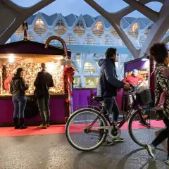 Gente pasea por puestos del **Valencia Christmas Market** bajo una estructura futurista.