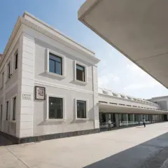 Edificio moderno y clásico en el **espacio Seneca Alicante**. Fachada gris, ventanas oscuras y un gran voladizo de hormigón.