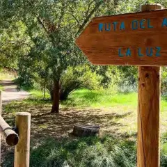 Cartel de madera indica "Ruta del Agua" y "La Luz" en Chelva. Camino de tierra con barandilla de madera.