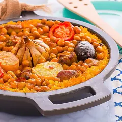 Delicioso arroz al horno con garbanzos, carne, tomate y una cabeza de ajo asada.