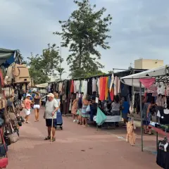 Gente paseando por el mercadillo de Canet de Berenguer, viendo bolsos, ropa y lencería expuestos en puestos.