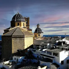 Altea vieille ville, con sus cúpulas y tejados blancos, se asoma al mar Mediterráneo bajo un cielo teñido de rosa y azul.