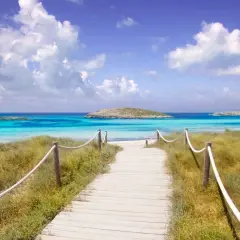 Camino de madera hacia las mejores playas del Levante. Aguas turquesas, arena blanca y un islote solitario.