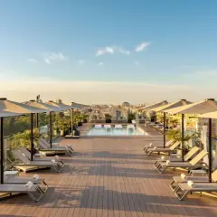 Terraza con piscina y tumbonas en el Novotel Valencia, vistas a la ciudad al atardecer.