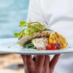 Delicioso plato de pescado a la parrilla con limón y tomate, servido en un restaurante en Cala Moraig.