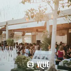 Gente disfrutando en Arribar, un lugar con ambiente de fiesta. El logo de @VLUE destaca.