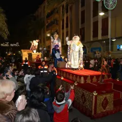 La cabalgata de Reyes en Valencia ilumina la noche con sus majestuosas carrozas y la multitud expectante. Melchor, Gaspar y Baltasar saludan a los niños.