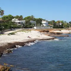 Un paseo junto a las mejores calas de Dénia, con casas blancas, palmeras y el mar azul.