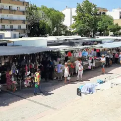 Gente paseando y comprando en el mercadillo de Jávea, con puestos de bolsos y ropa bajo toldos.