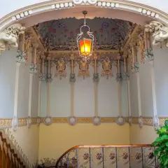 Detalles ornamentales de una casa modernista en Novelda, con una lámpara colgante y motivos florales en el techo.